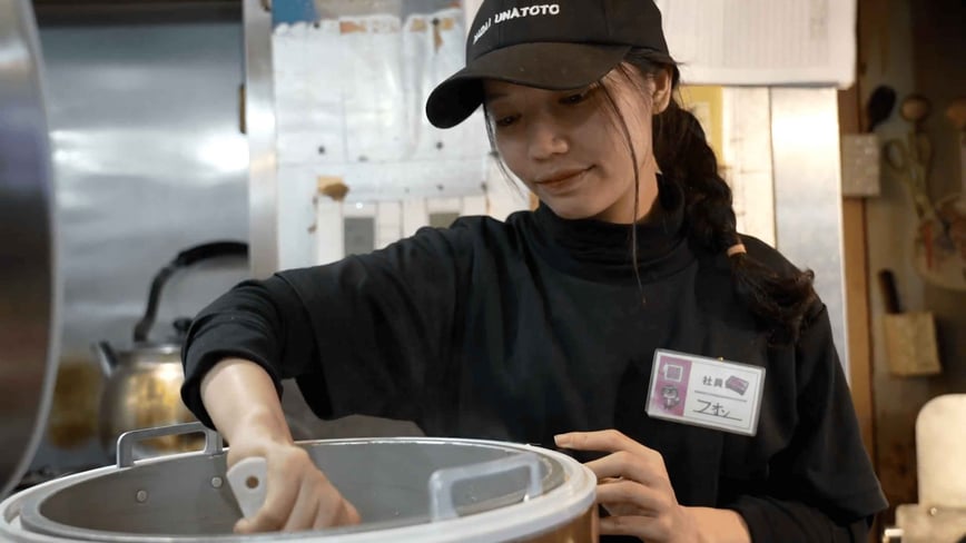 鰻屋の厨房でごはんをよそうフォンさんの写真
